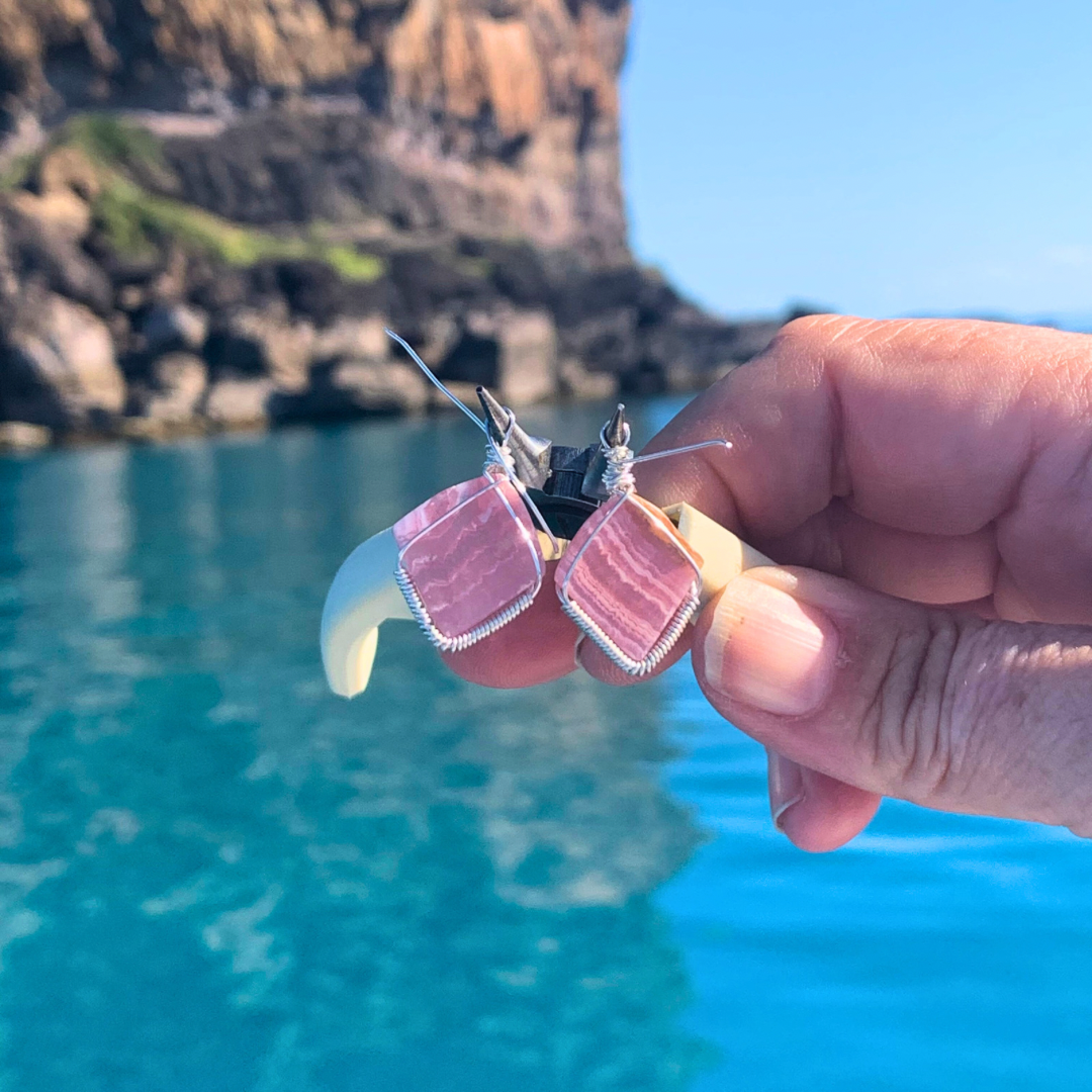 Ray of Sunshine Jewellery - stunning pink gemstones hand carved by me wrapped in Sterling Silver and hanging from my pliers as I make them sitting alongside an island in the great barrier reef