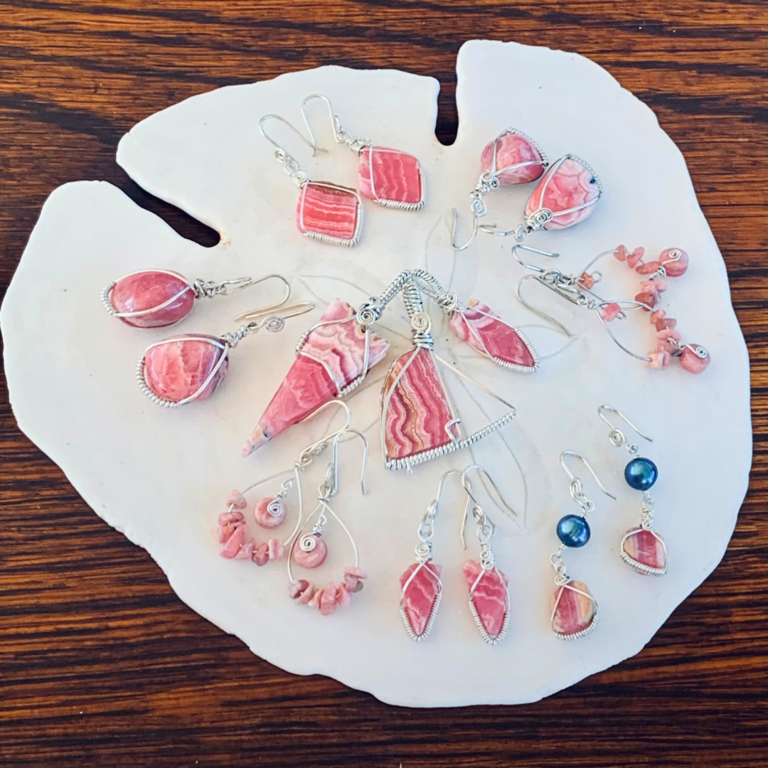 Ray of Sunshine Jewellery - a lovely platter of pink Rhodochrosite Sterling Silver wrapped gemstone jewellery sitting on a sand dollar shell.