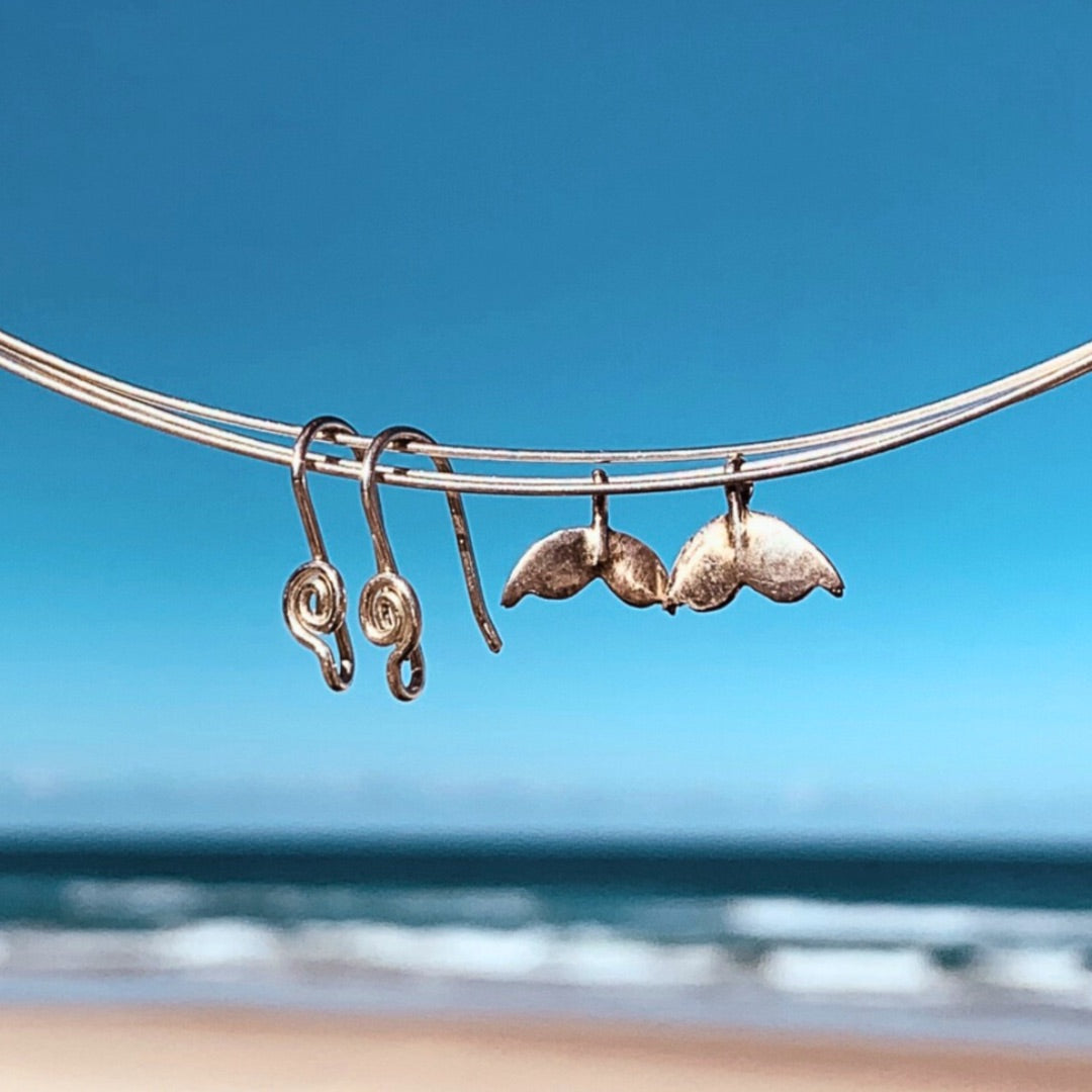 Ray of Sunshine Jewellery - my hand forged Sterling Silver ear wires and hand made whales tails hanging from silver wire overlooking the ocean with golden sand and spilling waves on the shoreline