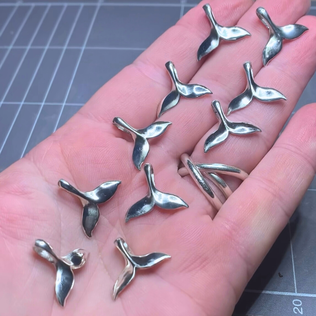 Ray of Sunshine Jewellery - 10 gorgeous hand made Sterling Silver whale tails resting on my open hand at the workbench