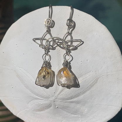 Ray of Sunshine Jewellery- Sterling Silver earrings with lotus flower and golden gemstones on a white sand dollar surface in the sunshine