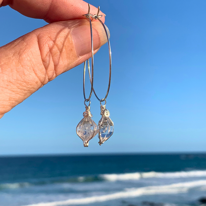 Ray of Sunshine Jewellery- Sterling Silver hoop earrings with clear Herkimer Diamonds held against a blue sky and ocean background