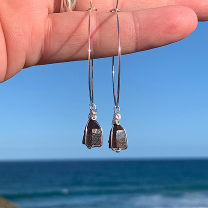 Ray of Sunshine Jewellery- Sterling Silver Hoop earrings with dark Smokey Quartz points held against a blue sky and ocean background