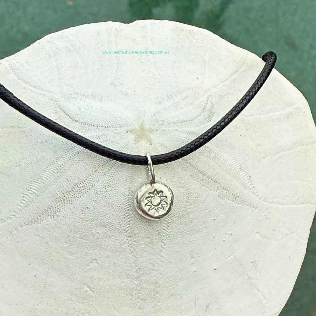 Ray of Sunshine Jewellery - handmade silver dollop of sunshine necklace sitting on a sand dollar shell
