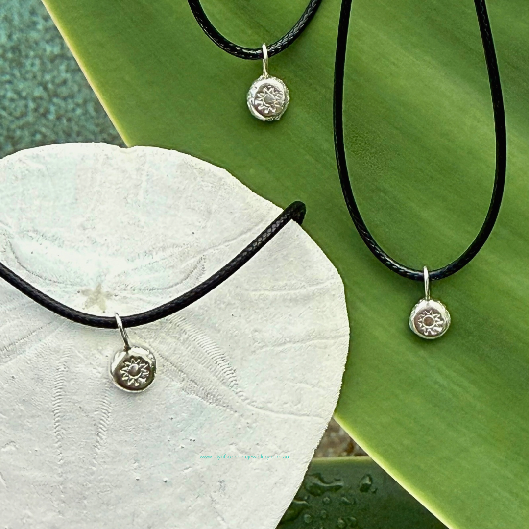 Ray of Sunshine Jewellery - dollops of sunshine necklaces sitting on a green leaf and a sand dollar shell