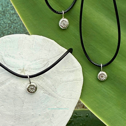 Ray of Sunshine Jewellery - dollops of sunshine necklaces sitting on a green leaf and a sand dollar shell