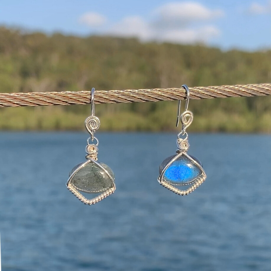 Ray of Sunshine Jewellery- Teardrop-shaped earrings with blue Labradorite gemstones hanging on a wire against a natural background.