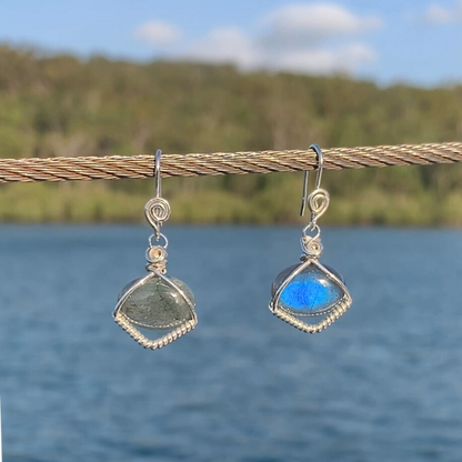 Ray of Sunshine Jewellery- Teardrop-shaped earrings with blue Labradorite gemstones hanging on a wire against a natural background.