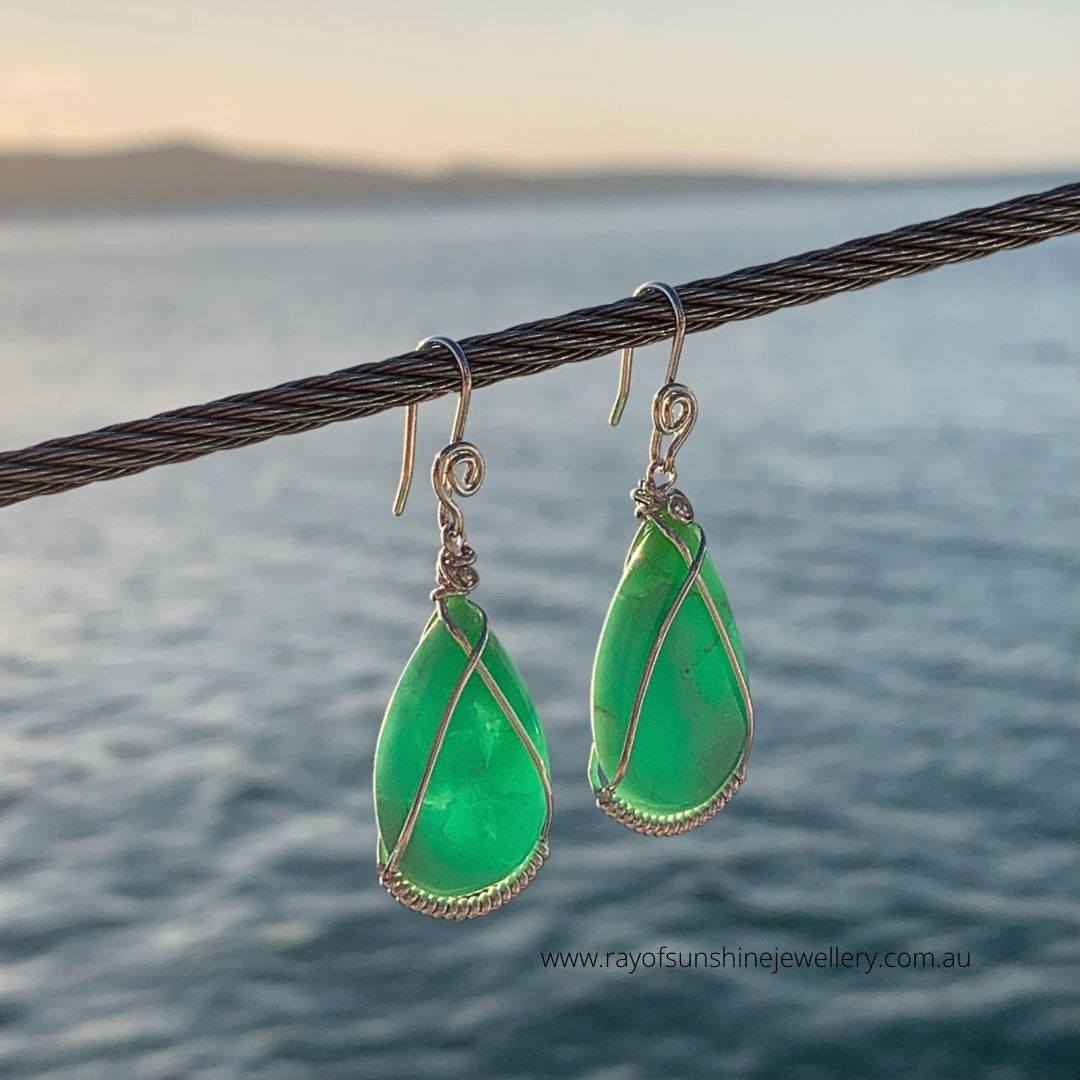 Ray of Sunshine Jewellery- Apple-Green Chrysoprase teardrop earrings with silver wire wrapping hanging on a wire against a blurred natural background.