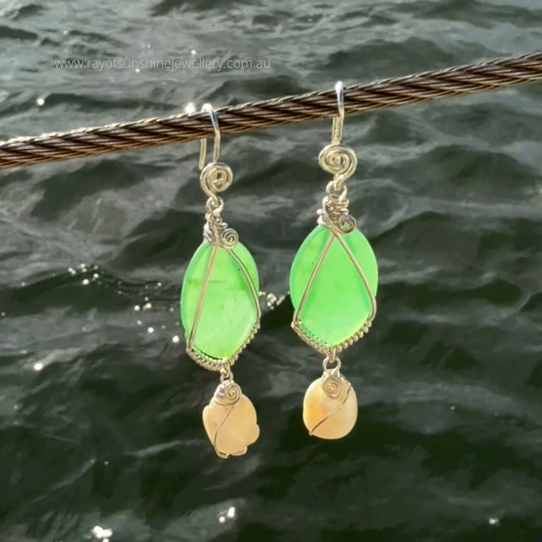 Ray of Sunshine Jewellery- Apple-Green Chrysoprase teardrop earrings with silver wrapping held over dark water background