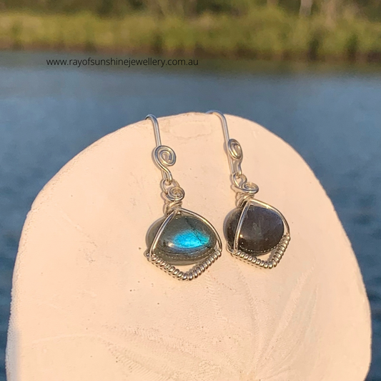 Ray of Sunshine Jewellery- dreamy blue Labradorite gemstones hanging on a sand dollar shell over water with blue skies in the background