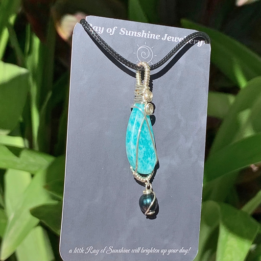 Turquoise blue amazonite pendant with balck tahitian pearl wrapped in silver wire on a ‘Ray of Sunshine Jewellery’ card with green leaves in the background