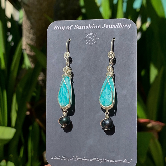 Turquoise Amazonite gemstone teardrop earrings with black tahitian pearls on a 'Ray of Sunshine Jewellery' card against a green leafy background.