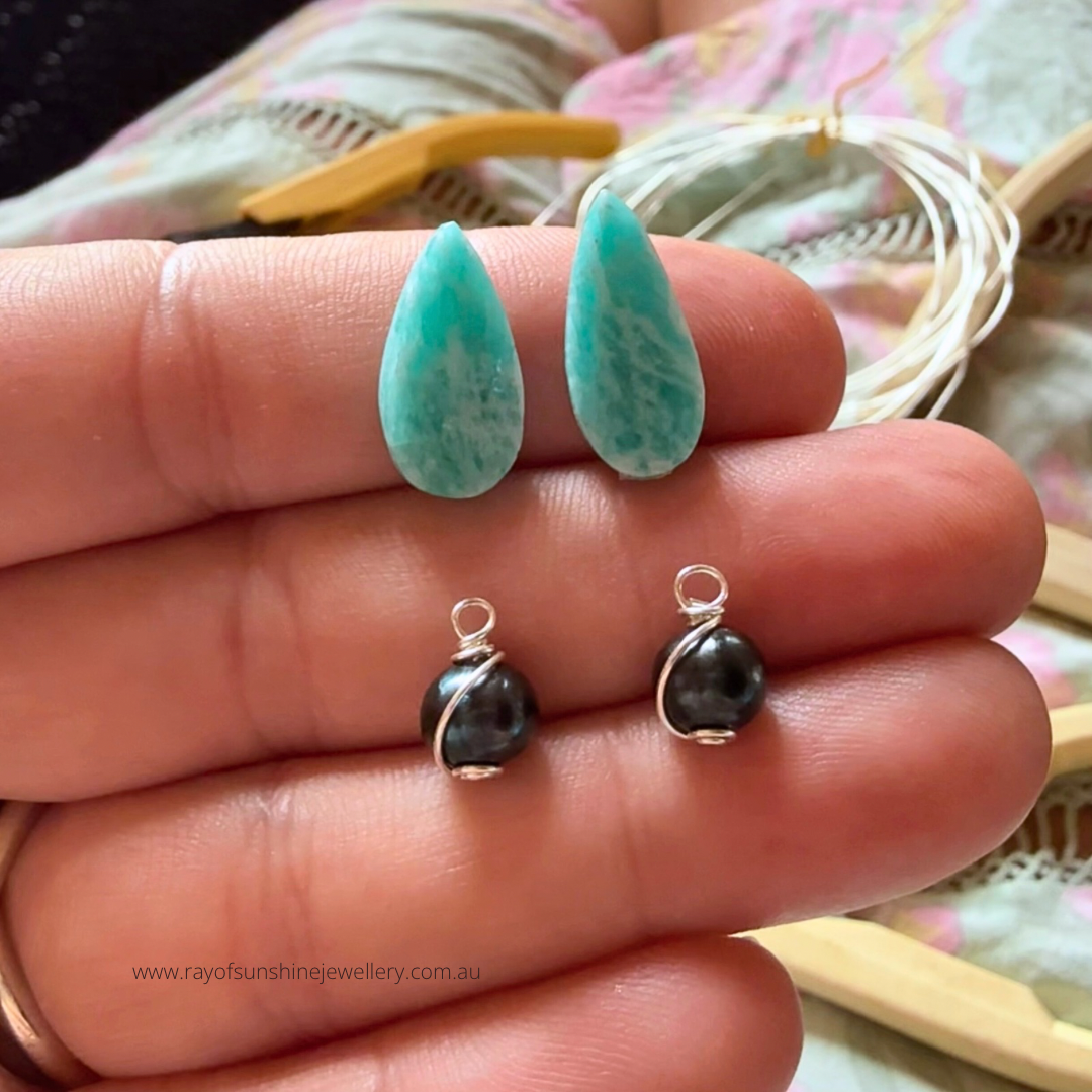 Turquoise amazonite teardrop-shaped gemstones and  tahitian black pearls twisted in silver wire on my hand.
