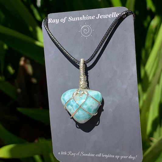 Swirly blue green gemstone necklace with a silver wire heart on a ‘Ray of Sunshine Jewellery’ card with green foliage in the background