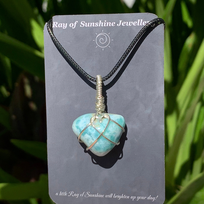 Blue green larimar gemstone, with a silver wire heart necklace on a ‘Ray of Sunshine Jewellery’ card with greenery in the background