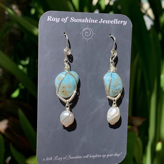 Blue and sandy swirl larimar gemstone and pearl earrings on a 'Ray of Sunshine Jewellery' card with green foliage in the background