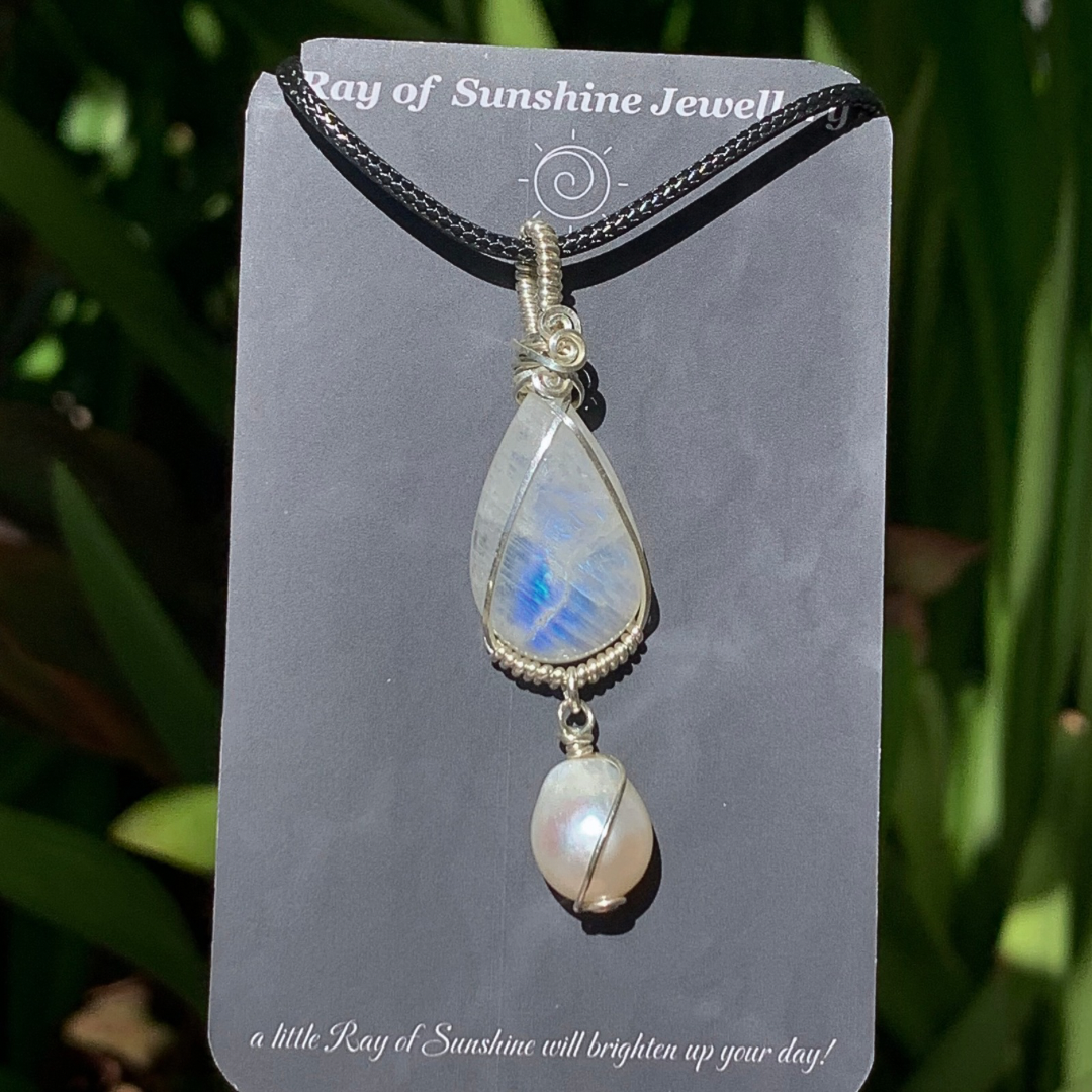 Blue moonstone and pearl pendant on a ‘Ray of Sunshine Jewellery’ card with greenery in the background