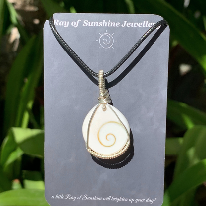 Necklace with a white shiva shell featuring a gold spiral design on a 'Ray of Sunshine Jewellery’ card with a green leafy background