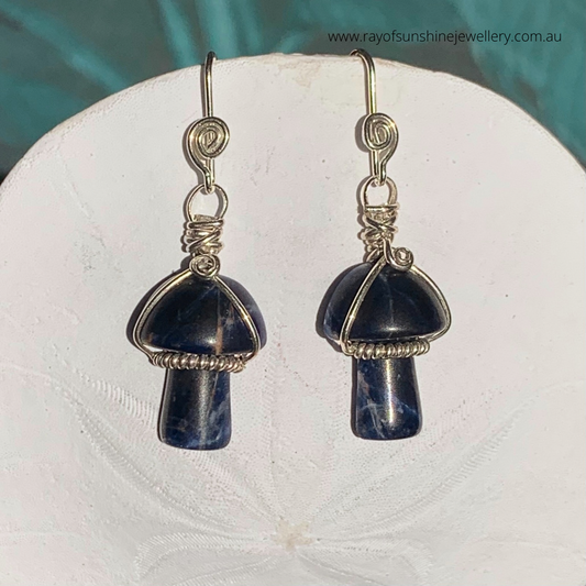 Ray of Sunshine Jewellery- Pair of mushroom-shaped earrings with Sodalite blue gemstones on a white sand dollar shell surface.