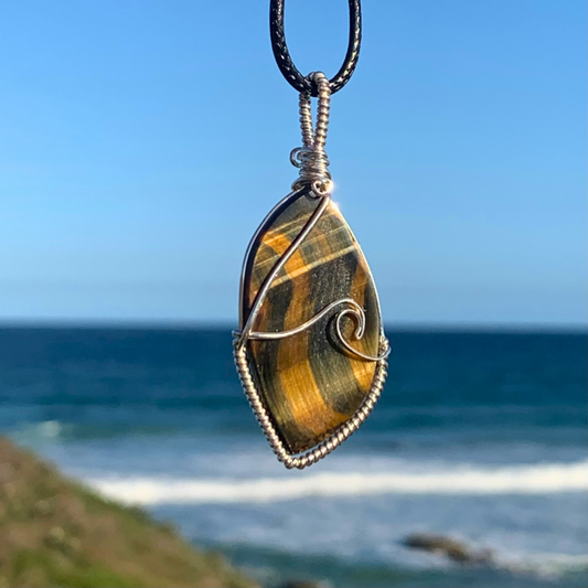 Ray of Sunshine Jewellery this gorgeous surfboard shaped stone has natural blue and gold shimmer that dances across the stone in a wave like pattern. Paired with my sterling silver wave of the day, this necklace is a statement piece. Pictured overlooking the ocean in the sunshine 