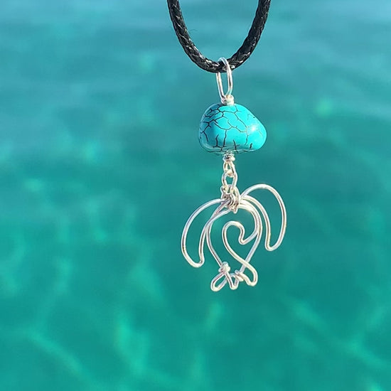 Ray of Sunshine Jewellery- my hand made Sea Turtles are hanging from a beautiful Turquoise Howlite bead and a black cord hanging over crystal clear turquoise coloured water in the sunshine. just stunning