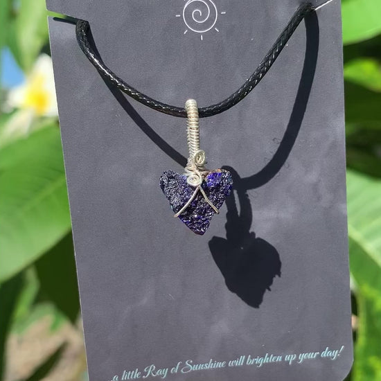Ray of Sunshine Jewellery azurite druzy heart is hugged in sterling silver hanging from my business card set against my frangipani tree in the sunshine