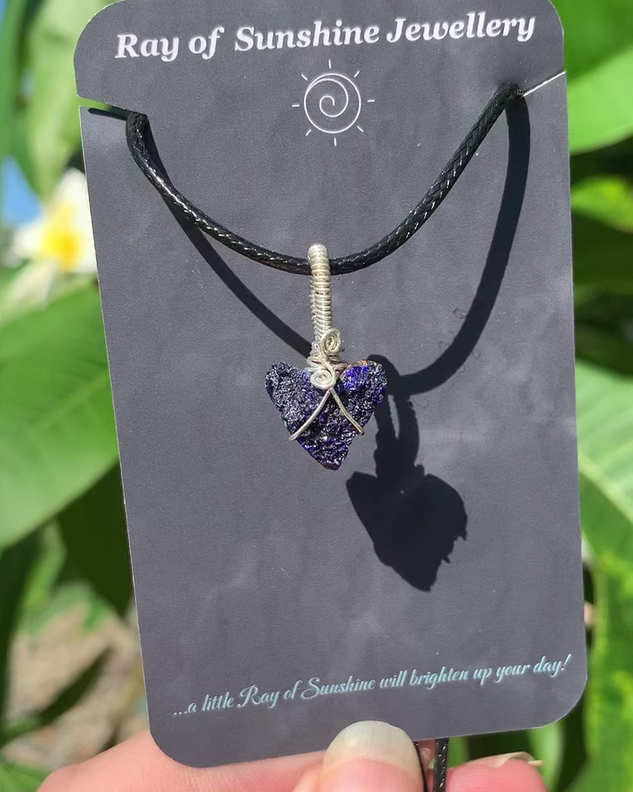 Ray of Sunshine Jewellery azurite druzy heart is hugged in sterling silver hanging from my business card set against my frangipani tree in the sunshine