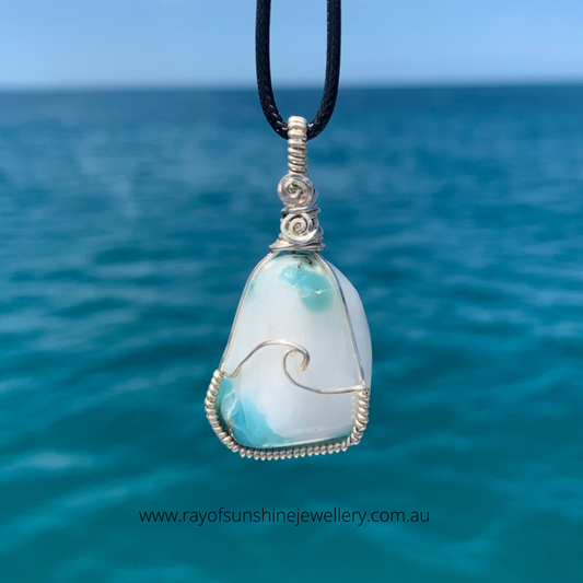 RAY OF SUNSHINE JEWELLERY - this chunky stone with a creamy white centre has a hand forged sterling silver ocean wave across the stone, big and chunky she hangs on a black cord over the ocean waters