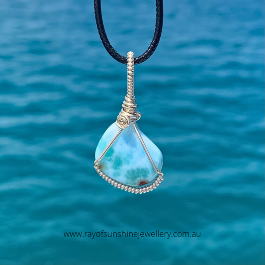 Ray of Sunshine Jewellery- the stunning blues and swirls captured within this stone look lovely as she hangs from a black cord over the turquoise ocean waters