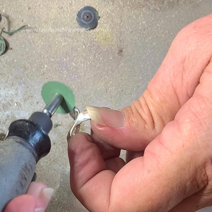 Donna sanding the flukes of a sterling silver whale tail pendant using a Dremel tool, handmade jewellery process, Ray of Sunshine Jewellery Northern NSW Australia

